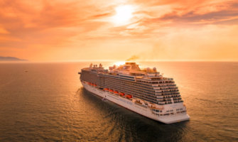 A huge cruise ship sailing into the sunset on calm waters