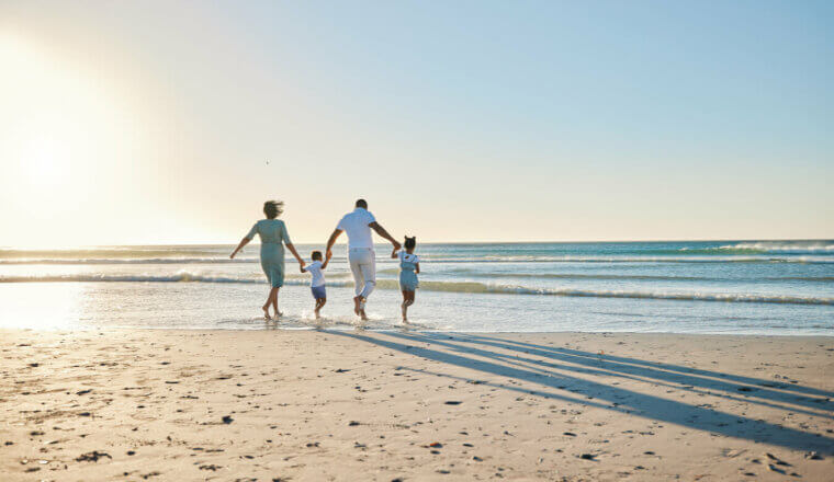 A traveling family at the beach standing near the water