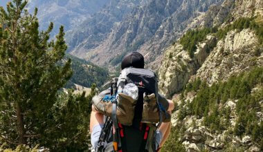 A guy wearing a backpack overlooking a mountain