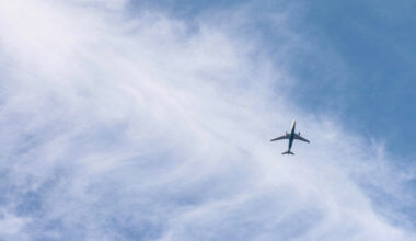 A lone commercial airplane flying against the bright blue sky
