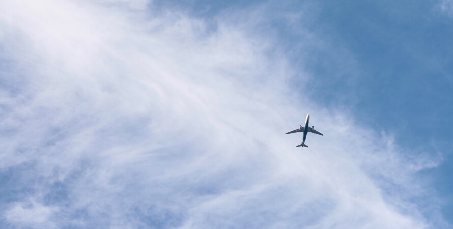 A lone commercial airplane flying against the bright blue sky