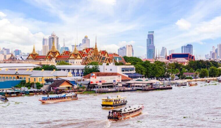 The skyline of Bangkok, Thailand with boats floating down the river