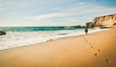 A solo female traveler walking alone on a sandy beach