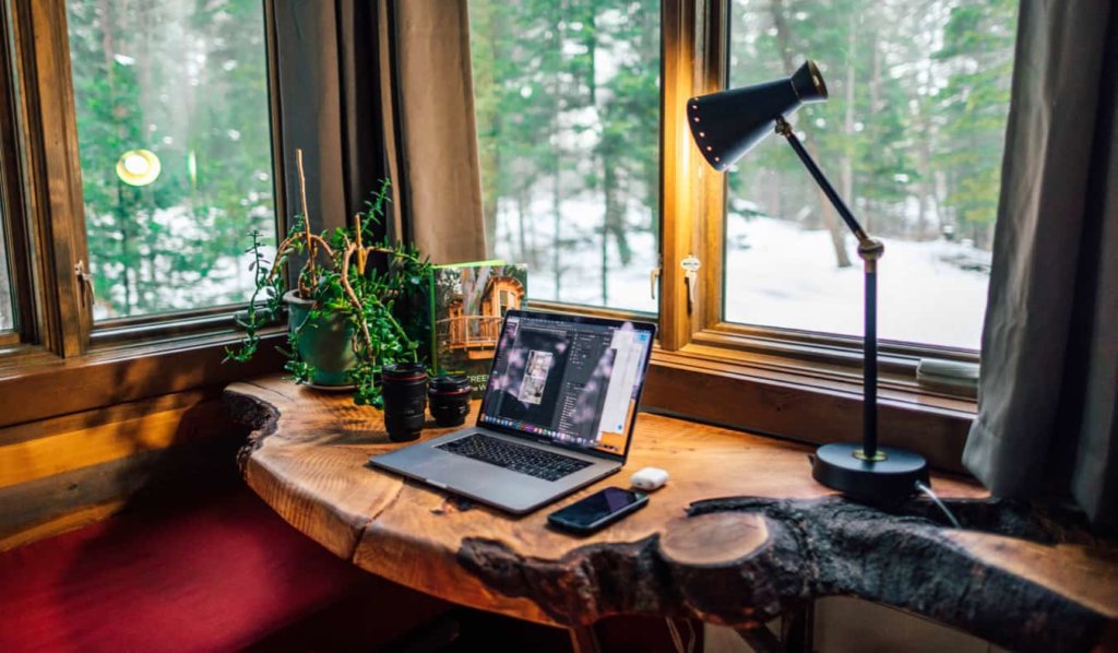 A cozy work from home office space with a laptop and camera lenses