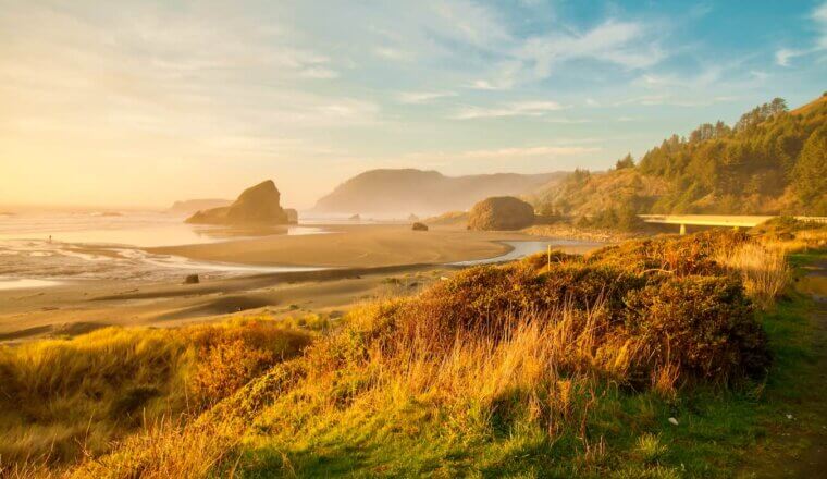A bright sunrise over a wide, empty beach along the beautiful Oregon coast
