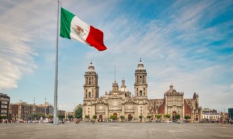 A large Mexican flag in front of one of the many historic buildings in Mexico City, Mexico
