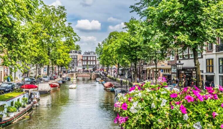 One of the many historic canals in Amsterdam surrounded by flowers