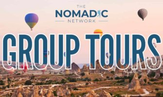 A desert landscape with hot air balloons and large text for Nomadic Matt's group tours