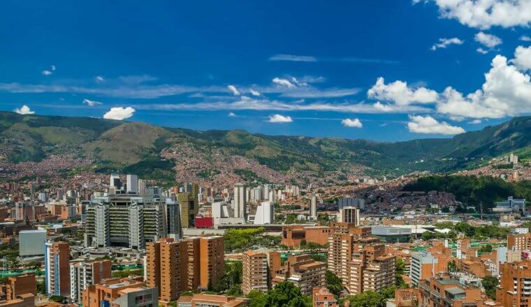 The skyline of colorful Medellin, Colombia surrounded by greenery on a sunny day