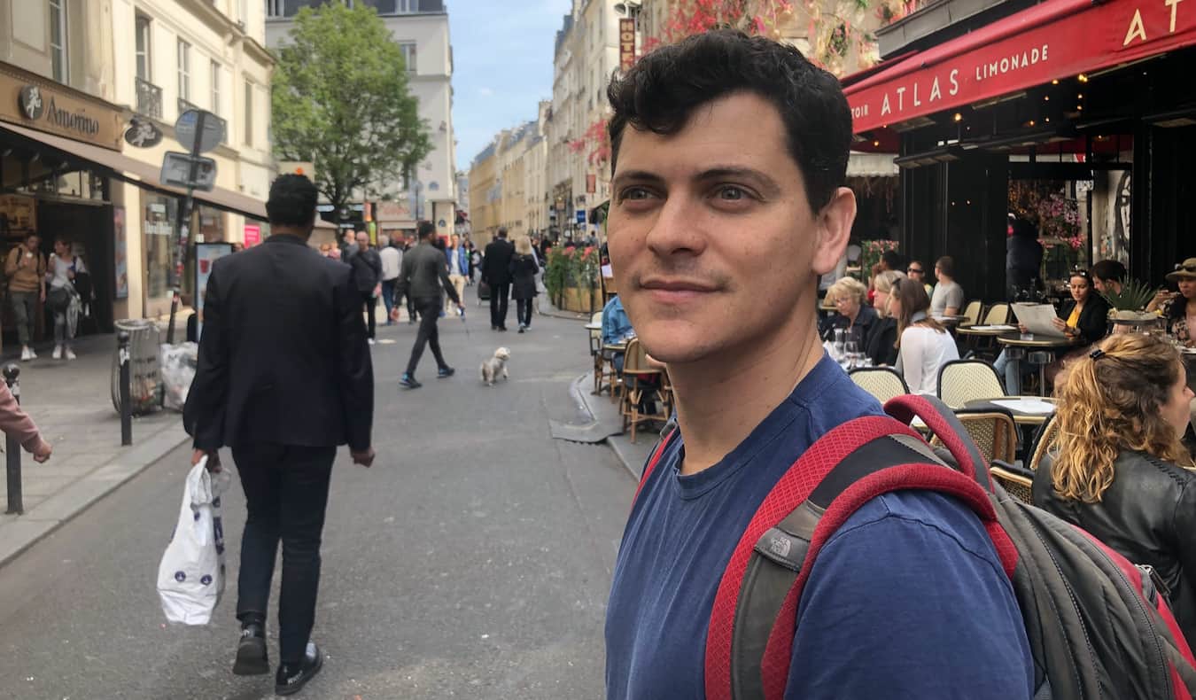 Nomadic Matt walking down a busy and anrrow street in Paris, France