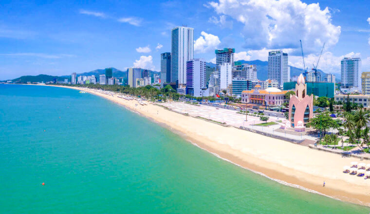 The beach scene along the coats of Nha Trang, Vietnam with the city skyline towering along the coastline