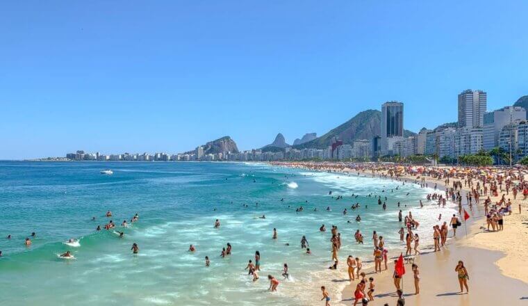People having fun in the ocean along a long stretch of beach lined with multistory buildings in Rio de Janeiro, Brazil