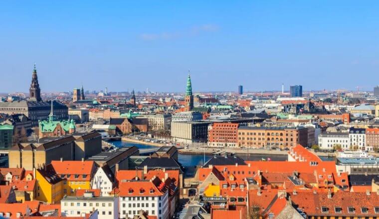Aerial view of Copenhagen, Denmark, with red rooftops and church steeples dotting the cityscape