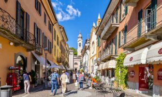 People exploring a narrow street in a colorful city in beautiful, sunny Italy