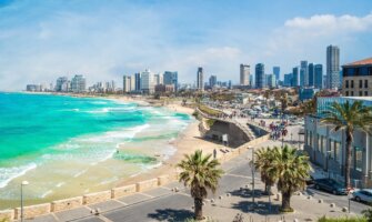 The city skyline in Tel Aviv, Israel, with a horseshoe-shaped beach, the azure blue ocean, and skyscrapers in the background
