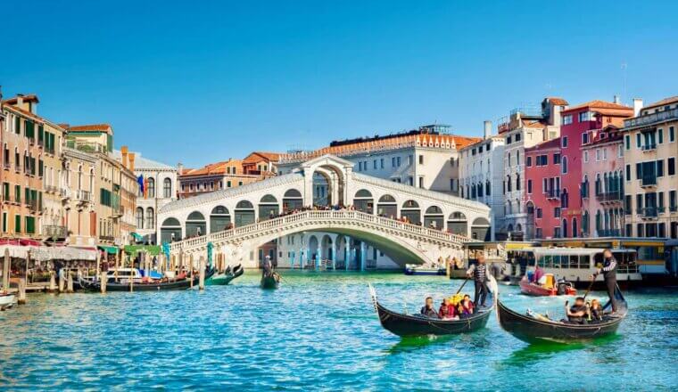 A sunny day in Venice, Italy as people ride gondolas in the large canals