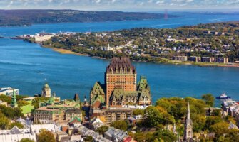 The skyline of Quebec City with the Frontenac Castle featuring prominently in the foreground and the deep blue of the Lawrence River in the background