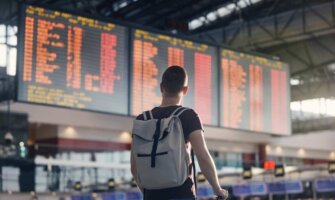 A man with a backpack on looks at an airport departures board full of red cancellations