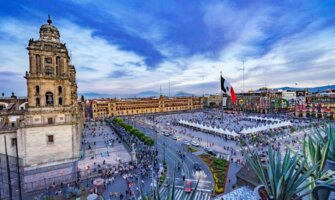 The beautiful Zocalo square at sunset, with the Metropolitan Cathedral, President's Palace, and huge Mexican flag in the center