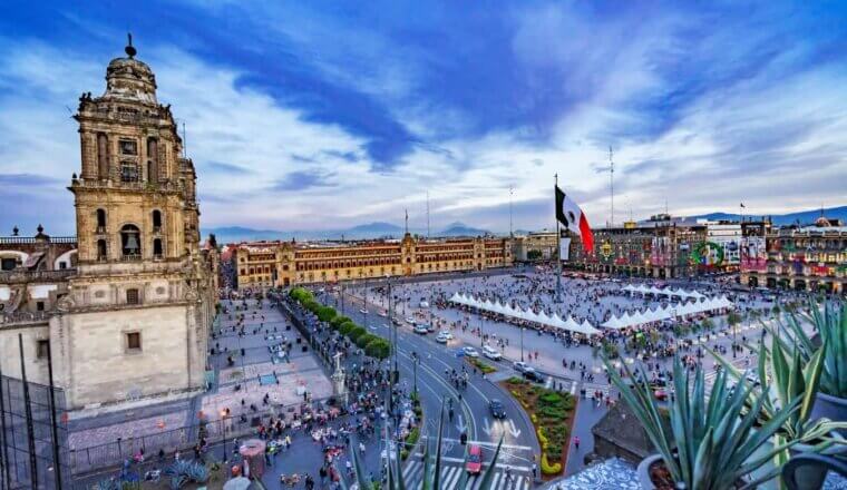 The beautiful Zocalo square at sunset, with the Metropolitan Cathedral, President's Palace, and huge Mexican flag in the center