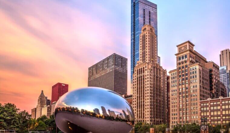 The famous Bean in Chicago at sunset, near the towering downtown of the city